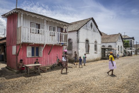 Einheimische schlendern durch eine Straße mit Wohngebäuden und Läden aus der Kolonialzeit