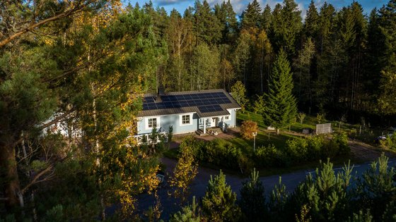 Ein skandinavisches Haus mit Fotovoltaikanlage Ein Haus mit einer Fotovoltaikanlage steht in einem Wald