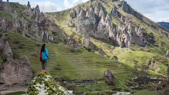 Eine Wanderin steht auf einem Felsvorsprung in Armenien und blickt in die Ferne.