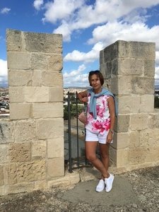 Unsere Reiseleiterin Lena Lagunaviciene steht an einem Mauergelände und lächelt frontal in die Kamera.