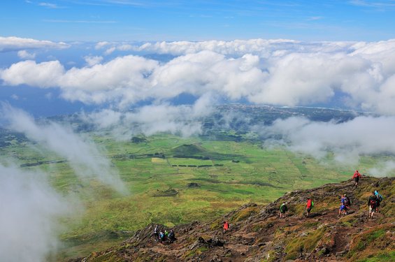 Eine Wandergruppe besteigt einen Berg und blickt auf das darunter liegende Tal.