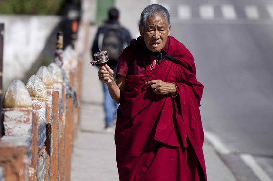 Mönch im Gewand hält eine Gebetsmühle in der Hand