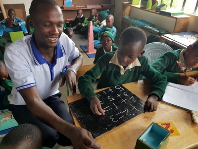 Ein Mitarbeiter des Africa Amini Alama-Projekts in Tansania unterrichtet Kinder im Klassenzimmer.