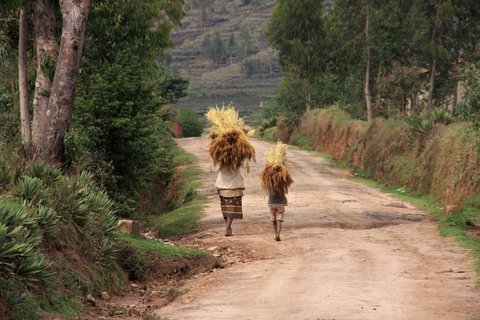 Eine Frau und ein Kind tragen Strohballen über dem Kopf auf einer Landstraße von Madagaskar