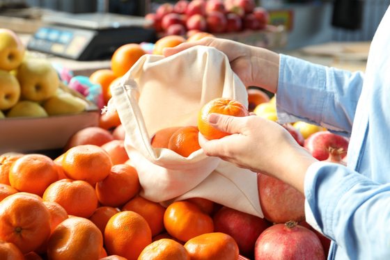Markteinkauf ohne Plastik Kunde füllt sein Baumwollökosäckchen mit Obst und Gemüse