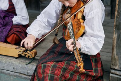 Eine junge Frau in Tracht spielt auf einer Geige.