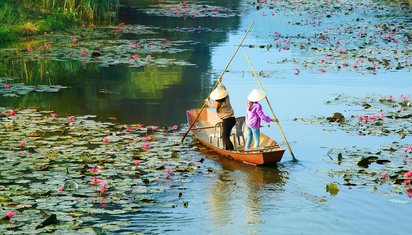 Wilde Natur in Vietnam Zwei Frauen paddeln mit ihrem Boot über einen Fluss in Vietnam.
