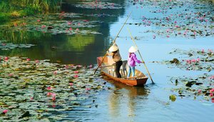 Zwei Frauen paddeln mit ihrem Boot über einen Fluss in Vietnam.