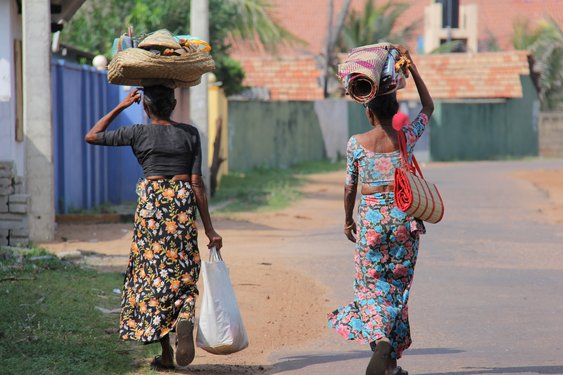 zwei Einheimische Frauen tragen Einkäufe auf dem Kopf