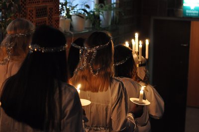 Weiß gekleidete Mädchen laufen mit Kerzen durch ein Gebäude.