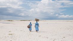 Zwei Frauen vom Seaweed Center auf Sansibar gehen entlang eines Strandes.