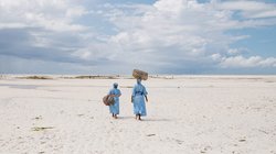 Zwei Frauen vom Seaweed Center auf Sansibar gehen entlang eines Strandes.