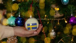 An einem Weihnachtsbaum hängt eine Kugel mit einer Schweden-Flagge