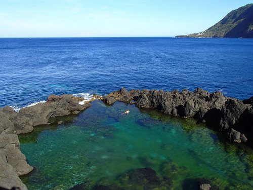 Ein Mann genießt das Bad im Naturpool bei Faja do Ouvidor auf Sao Jorge.