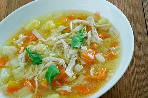 Ein tiefer Teller mit Hühnersuppe auf einem Holztisch