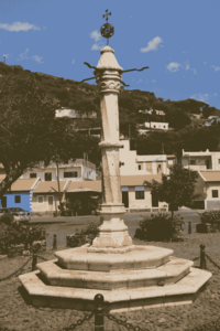 In der Mitte eines von Häusern umgebenen Platzes steht eine Steinsäule auf einem Sockel. sie hat früher als Pranger fungiert.