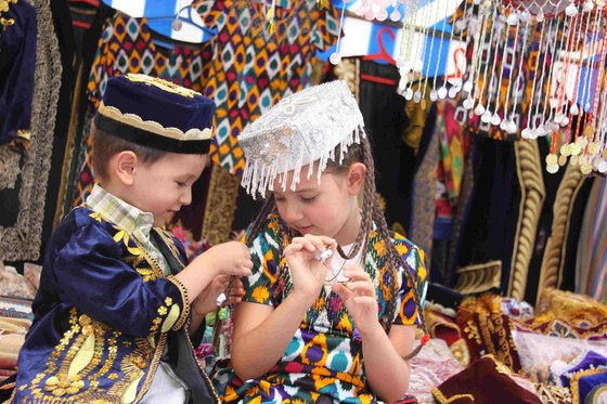 Ein junge und ein Mädchen sitzen in bunter Kleidung nebeneinander